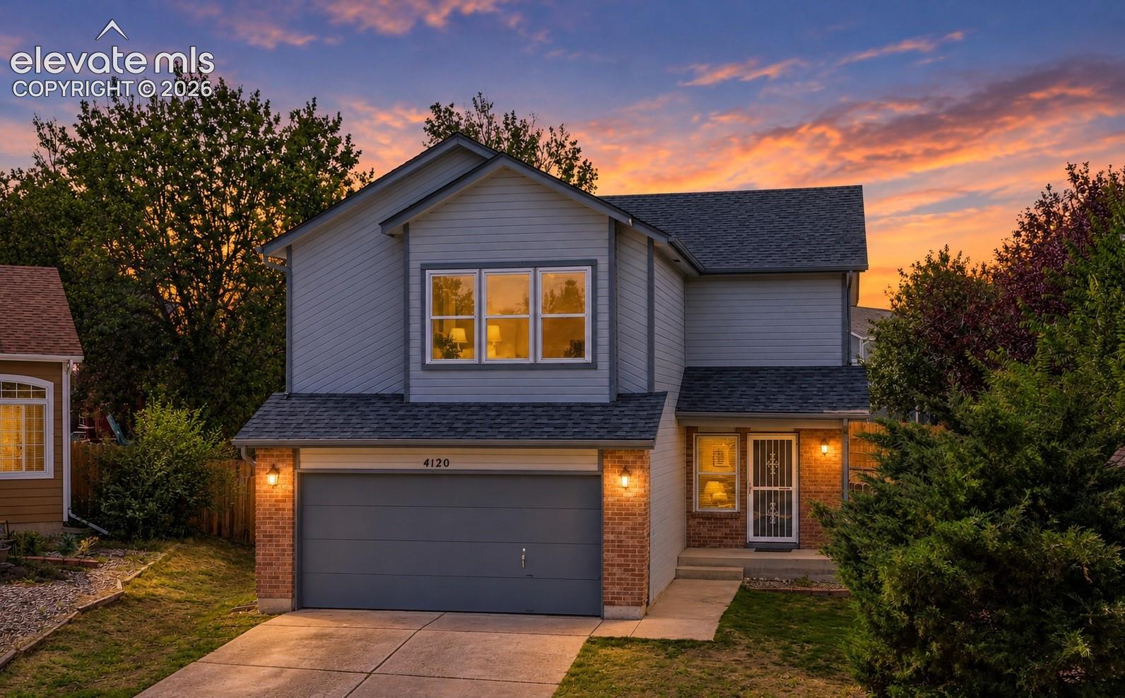 Two-story residence featuring light blue siding, brick accents, and a dark shingle roof