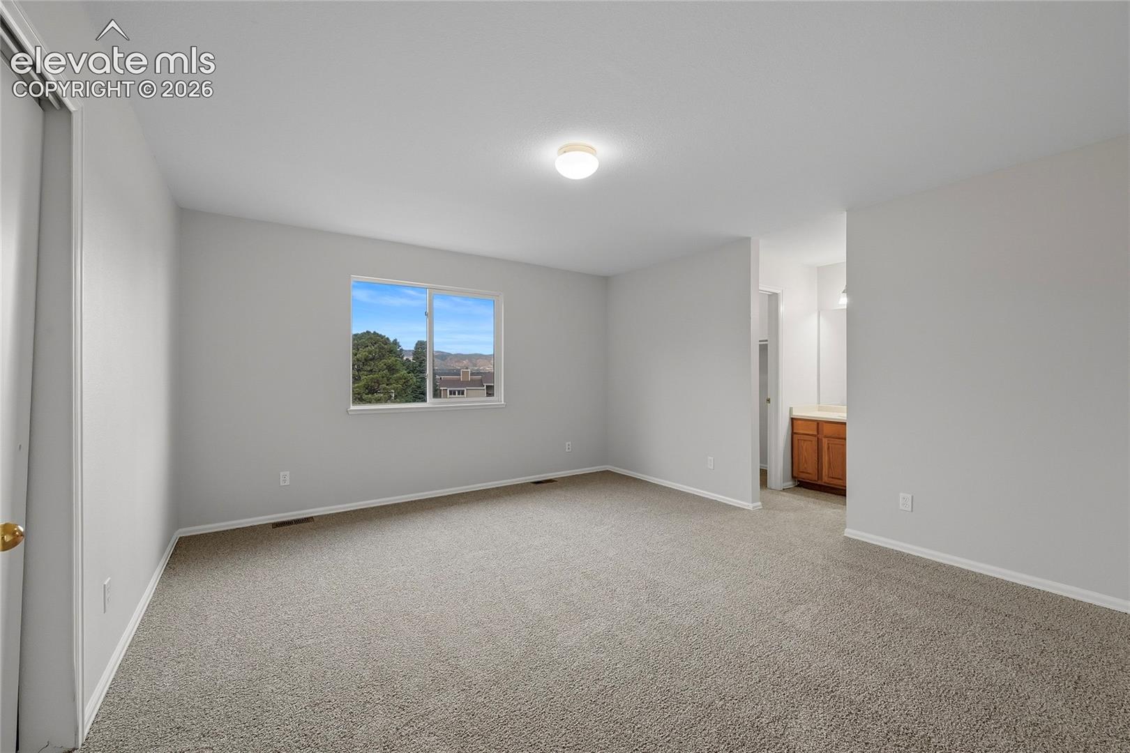 Room with neutral wall paint, wall-to-wall carpeting, and a sliding window