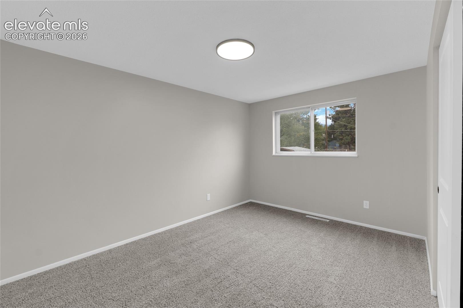 Neutral gray wall paint with gray carpet flooring, recessed lighting, and a white-framed window