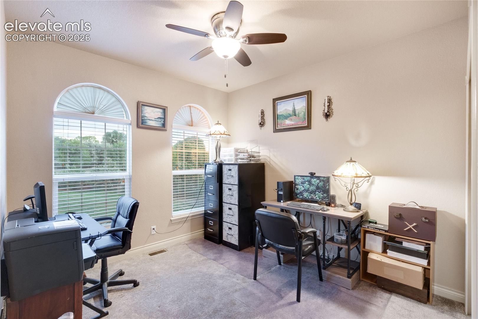 Main level secondary bedroom being used as a home office, large windows allowing in lots of natural light