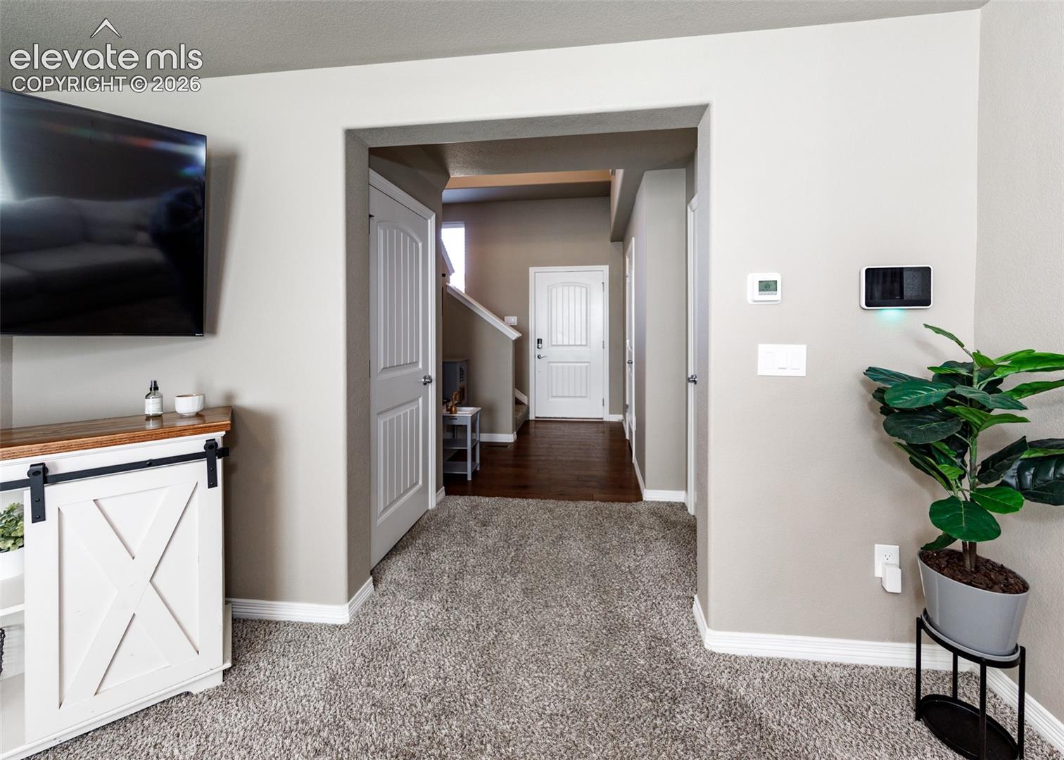 Neutral-toned interior featuring textured carpeting, paneled interior doors, and integrated smart home control panel