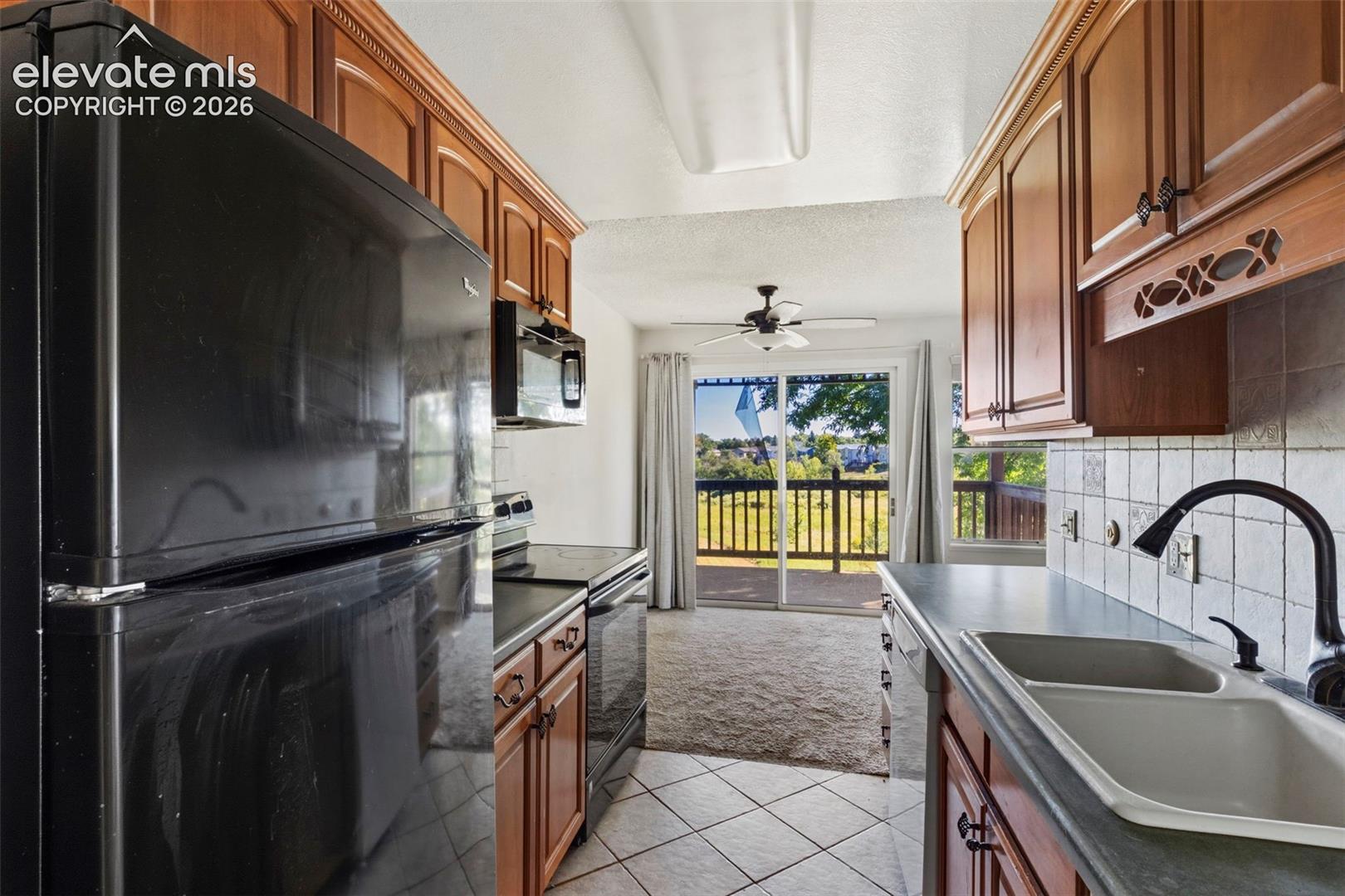 Galley kitchen featuring wood cabinetry, tile flooring, and a double-basin sink with a gooseneck faucet