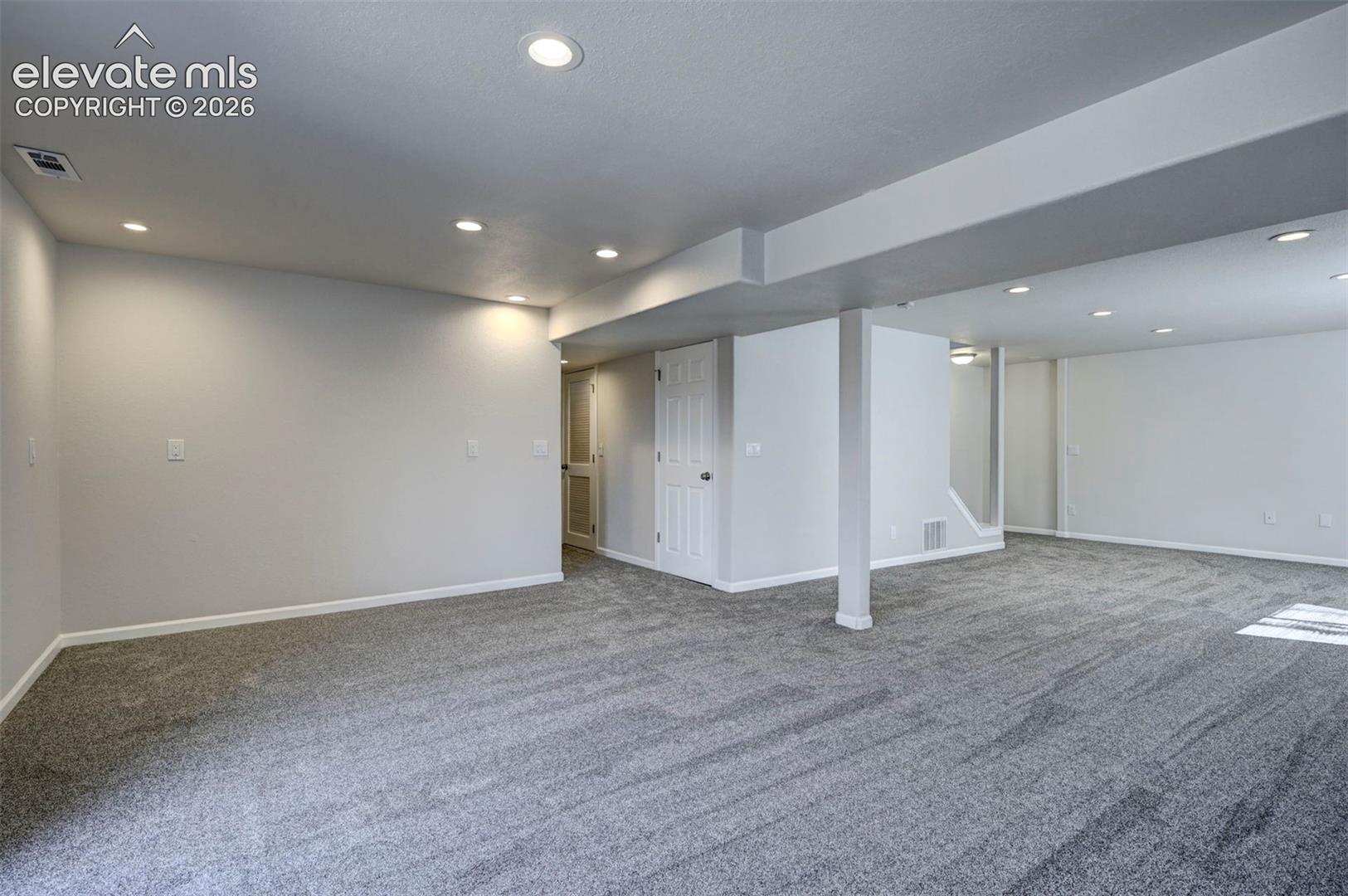 Open-concept interior space featuring neutral wall paint, recessed lighting, plush wall-to-wall carpeting, and a structural support column