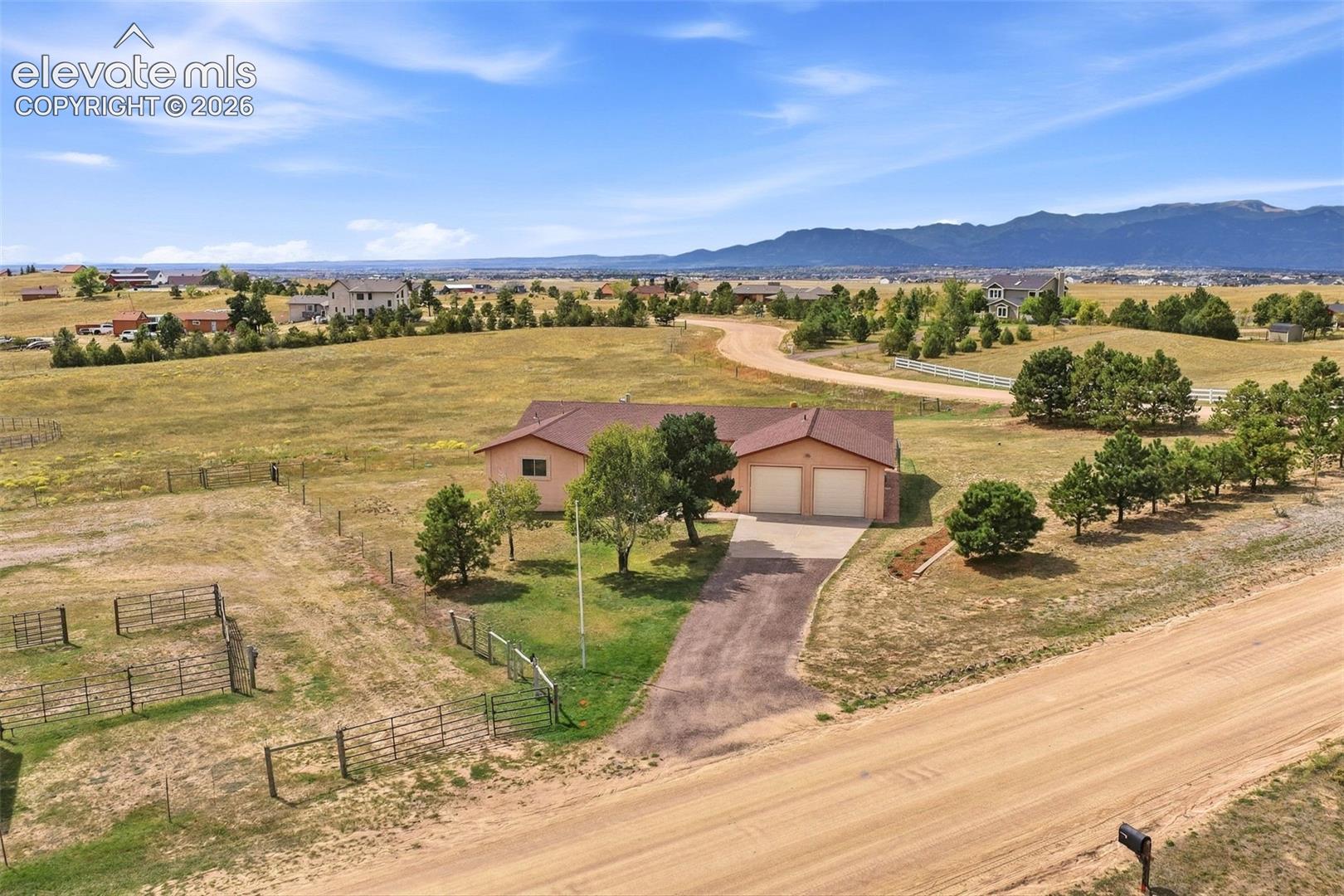 Expansive lot with a ranch-style home featuring an attached two-car garage, mature trees, and fencing