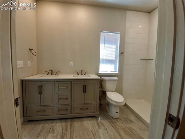 Double vanity with quartz counters, undermount sinks, and walk-in shower with tile surround