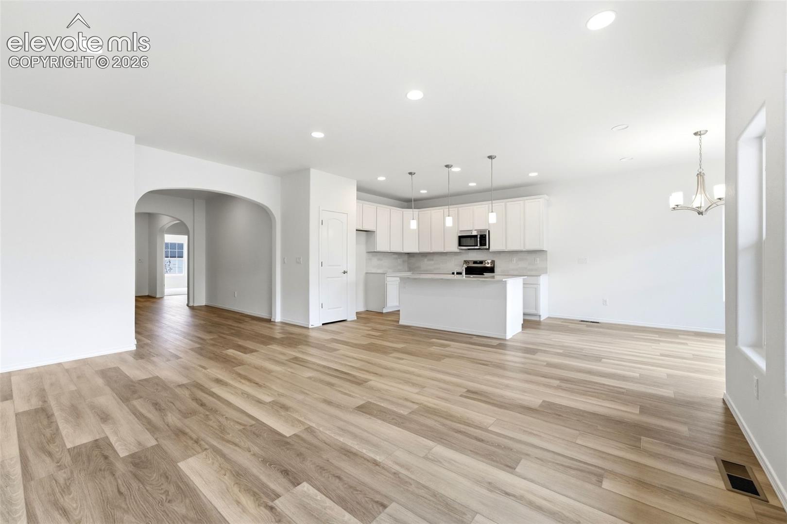 Open-concept kitchen featuring white cabinetry, a central island, recessed lighting, and wood-finish flooring
