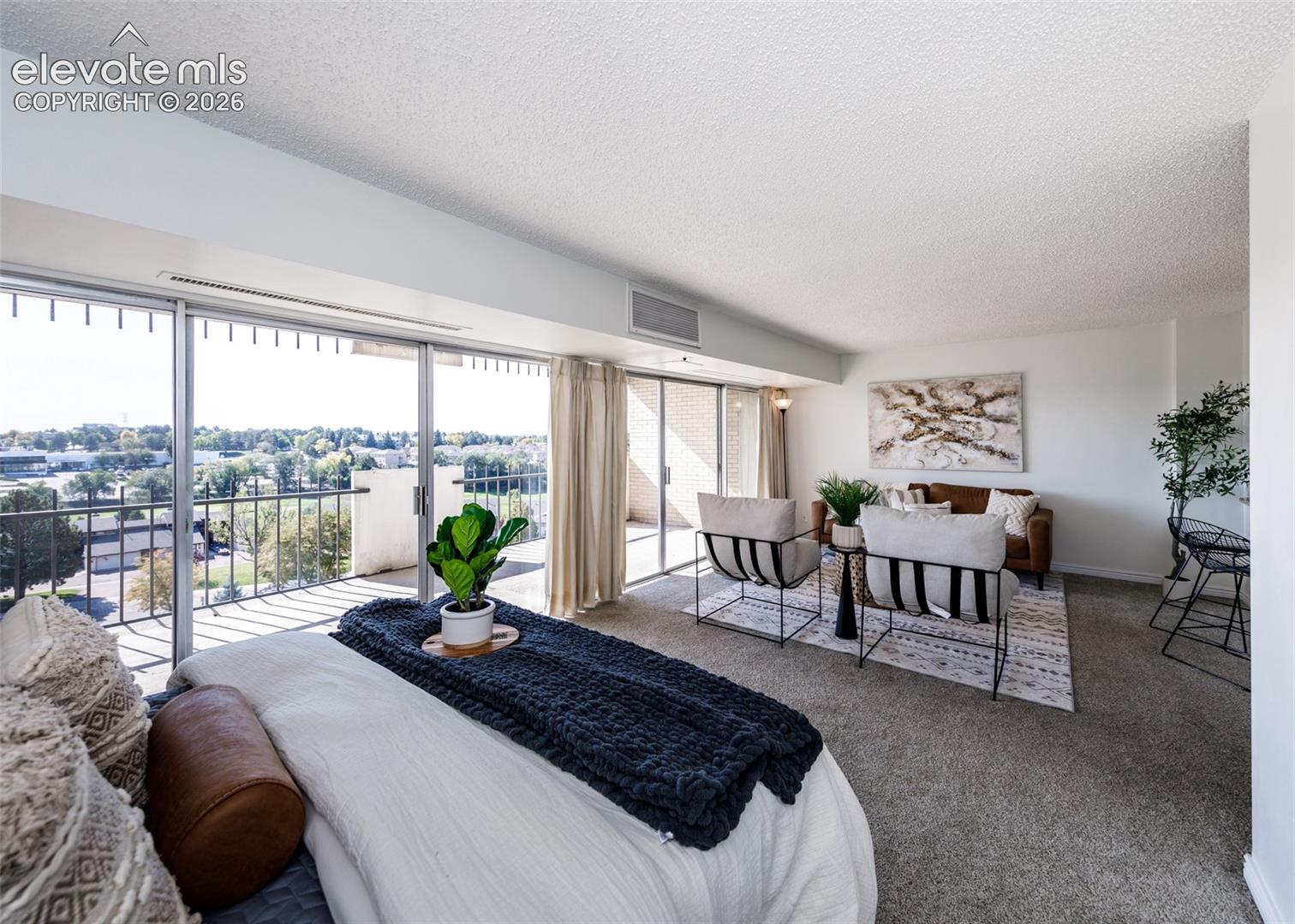 Floor-to-ceiling sliding glass doors, carpeted flooring, metal-railing balcony, and neutral wall finishes