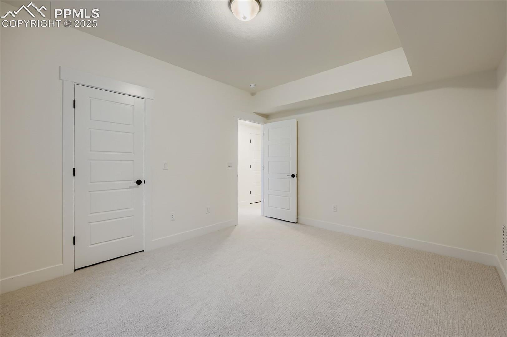 Unfurnished bedroom with light carpet and baseboards