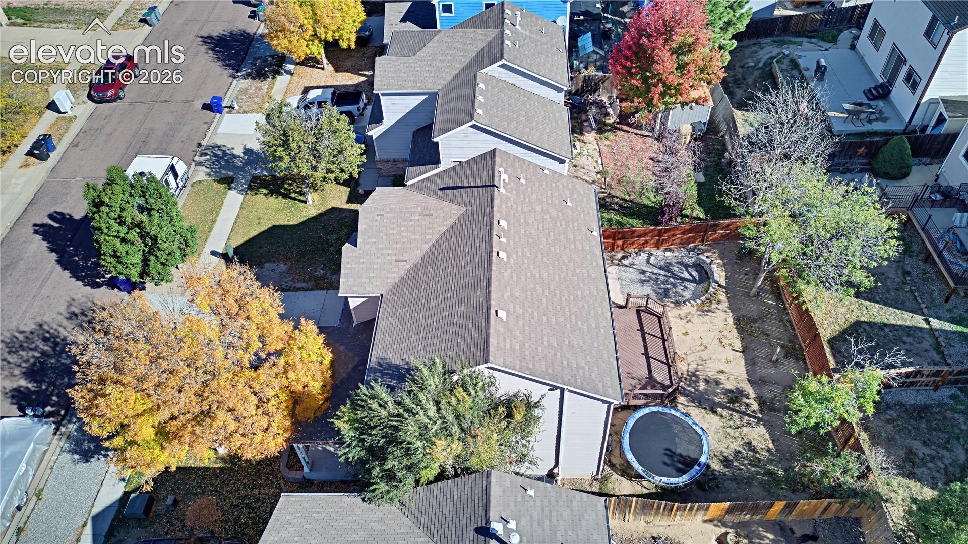 Aerial perspective featuring a multi-pitched asphalt shingle roof, a rear wood deck, and a fenced backyard