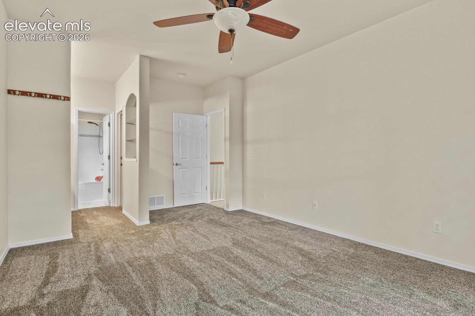 Carpeted flooring, ceiling fan with light fixture, built-in wall niche, and six-panel interior doors