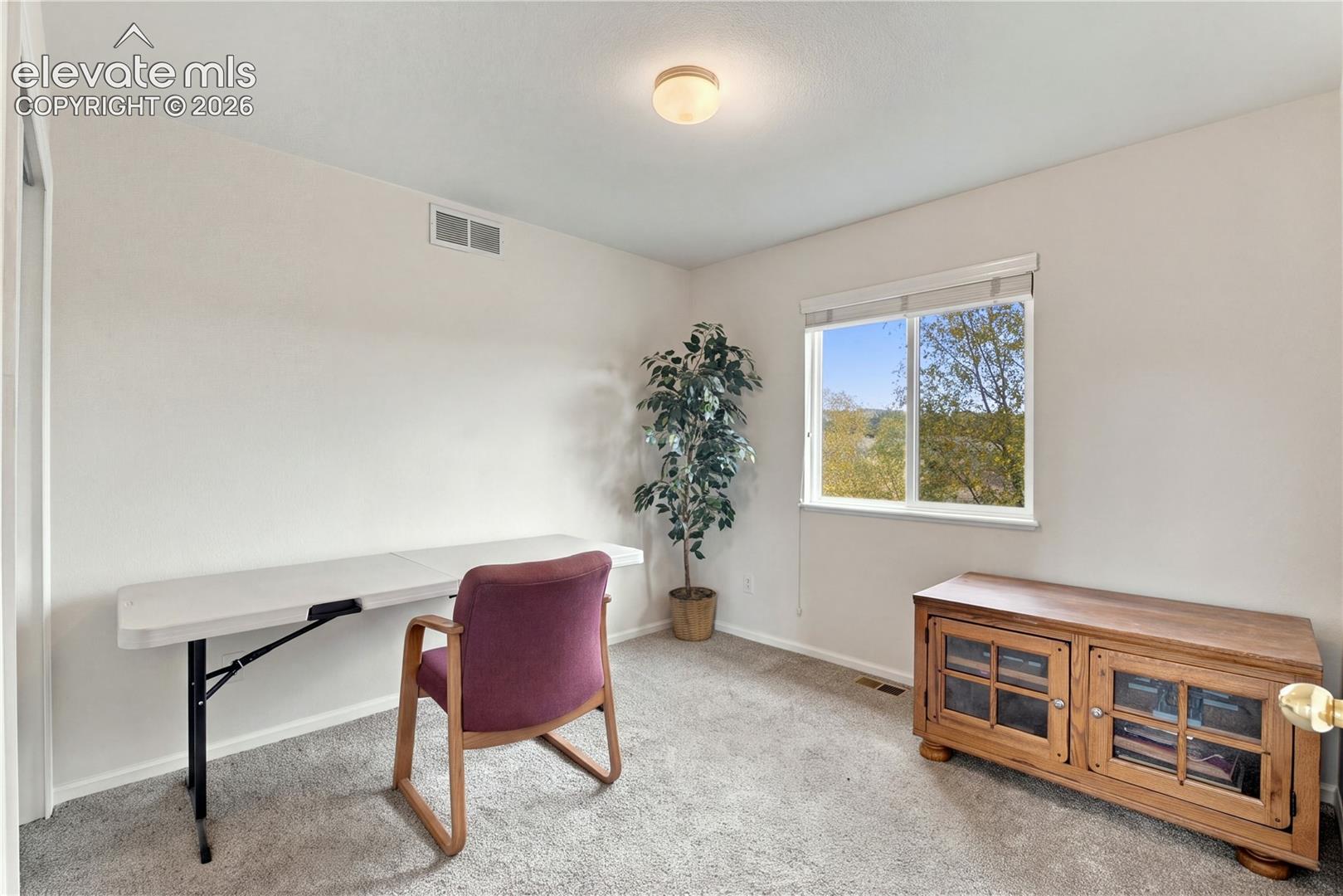 Neutral-toned interior space featuring wall-to-wall carpeting and a single-pane window with blinds