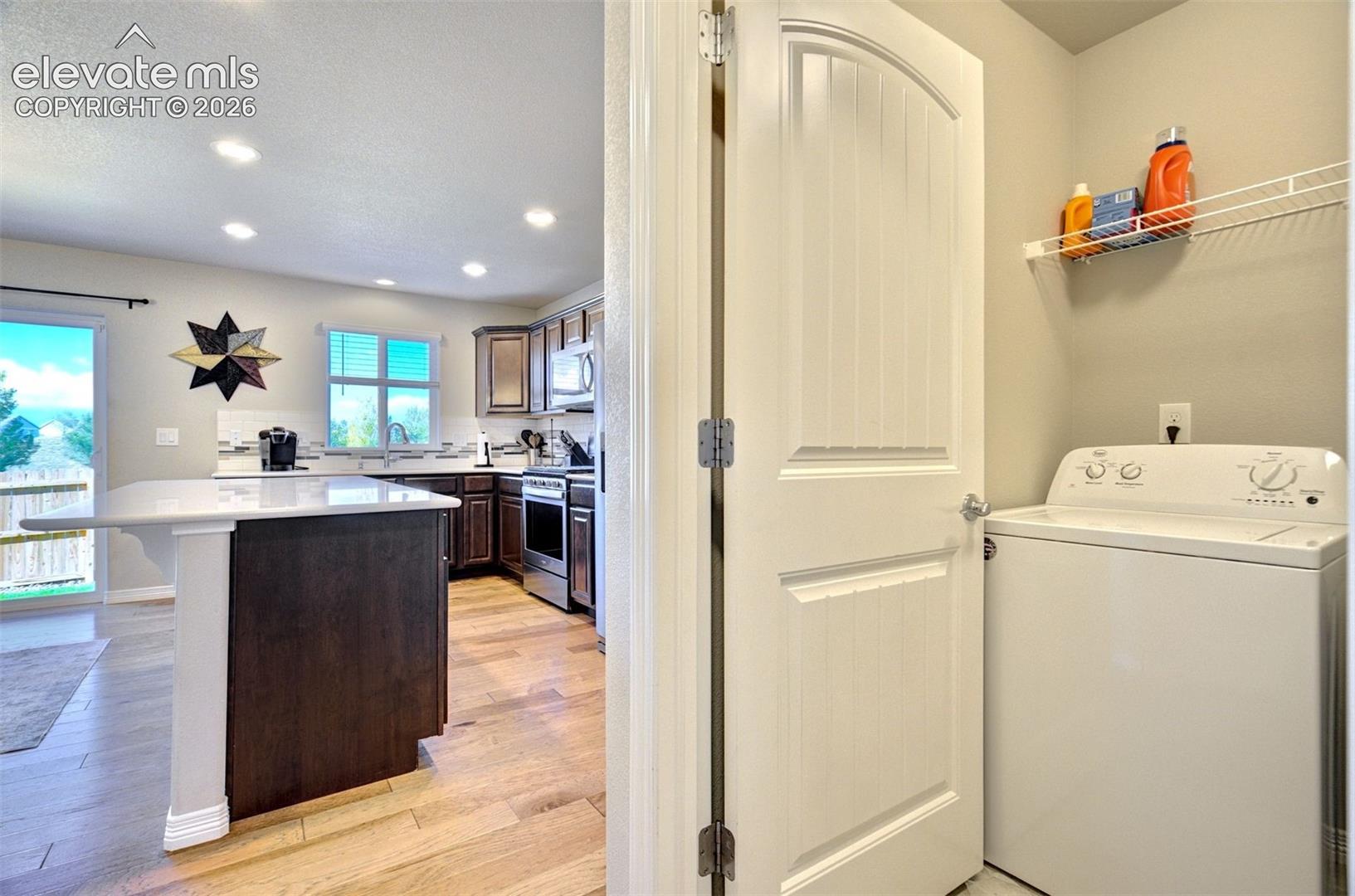Kitchen featuring a central island with a quartz countertop, wood-finish flooring, recessed lighting, and dark cabinetry