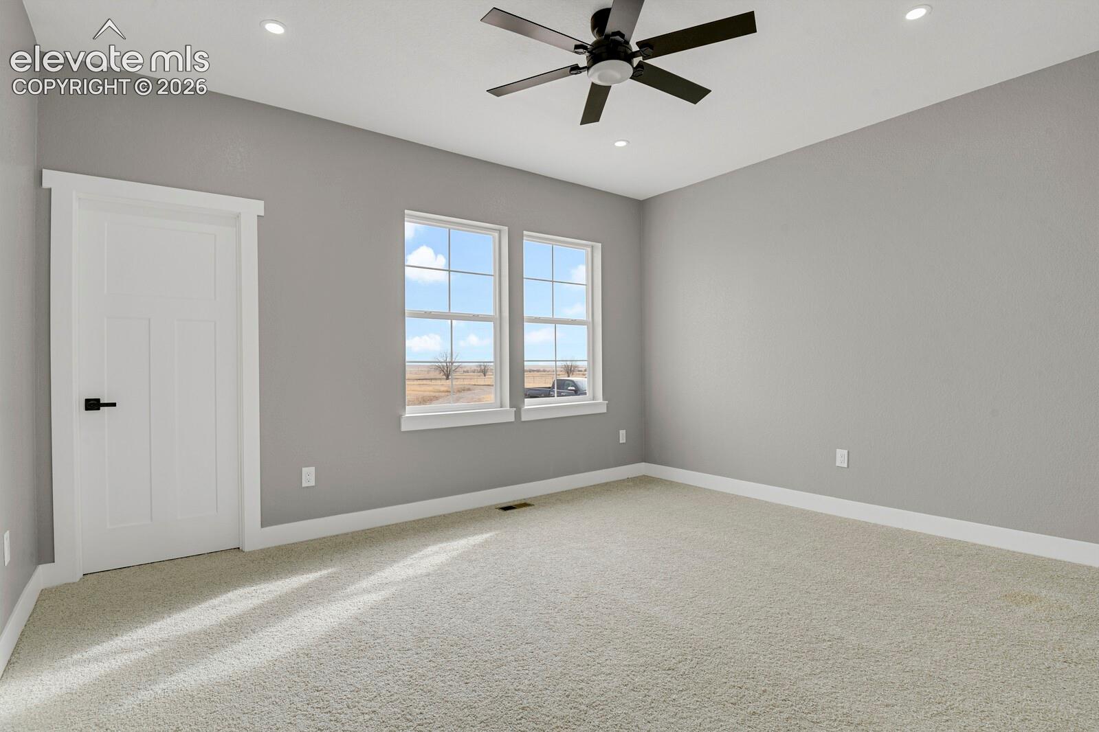 Recessed ceiling lighting, ceiling fan, carpeted flooring, and two paneled windows with white trim
