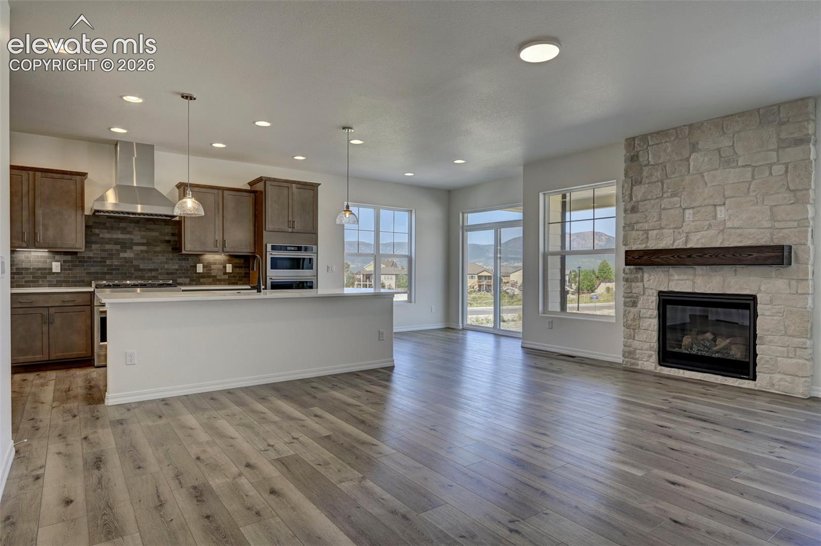 gas fireplace with stonework to ceiling and wood mantel; kitchen with island and breakfast nook with access to rear patio