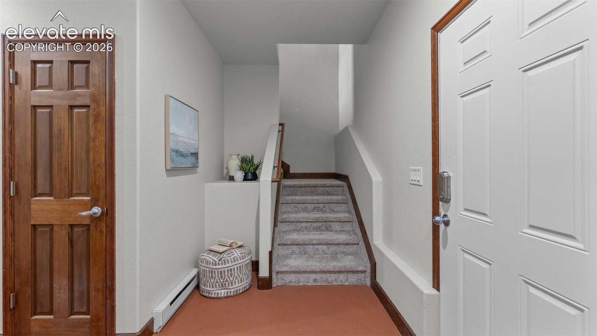 Entryway featuring a six-panel wood door, crisp neutral wall paint, carpeted staircase with a wood handrail, and a secondary six-panel wood door