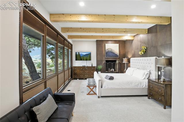 Bedroom with beam ceiling and light colored carpet