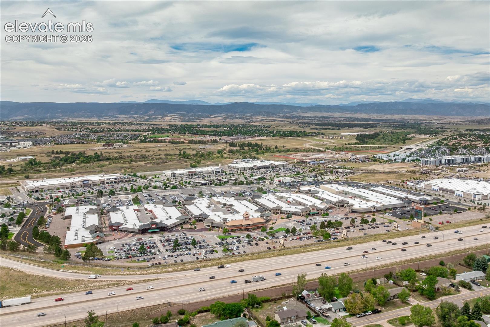 Aerial perspective of regional commercial development featuring expansive parking facilities and mountain horizon backdrop