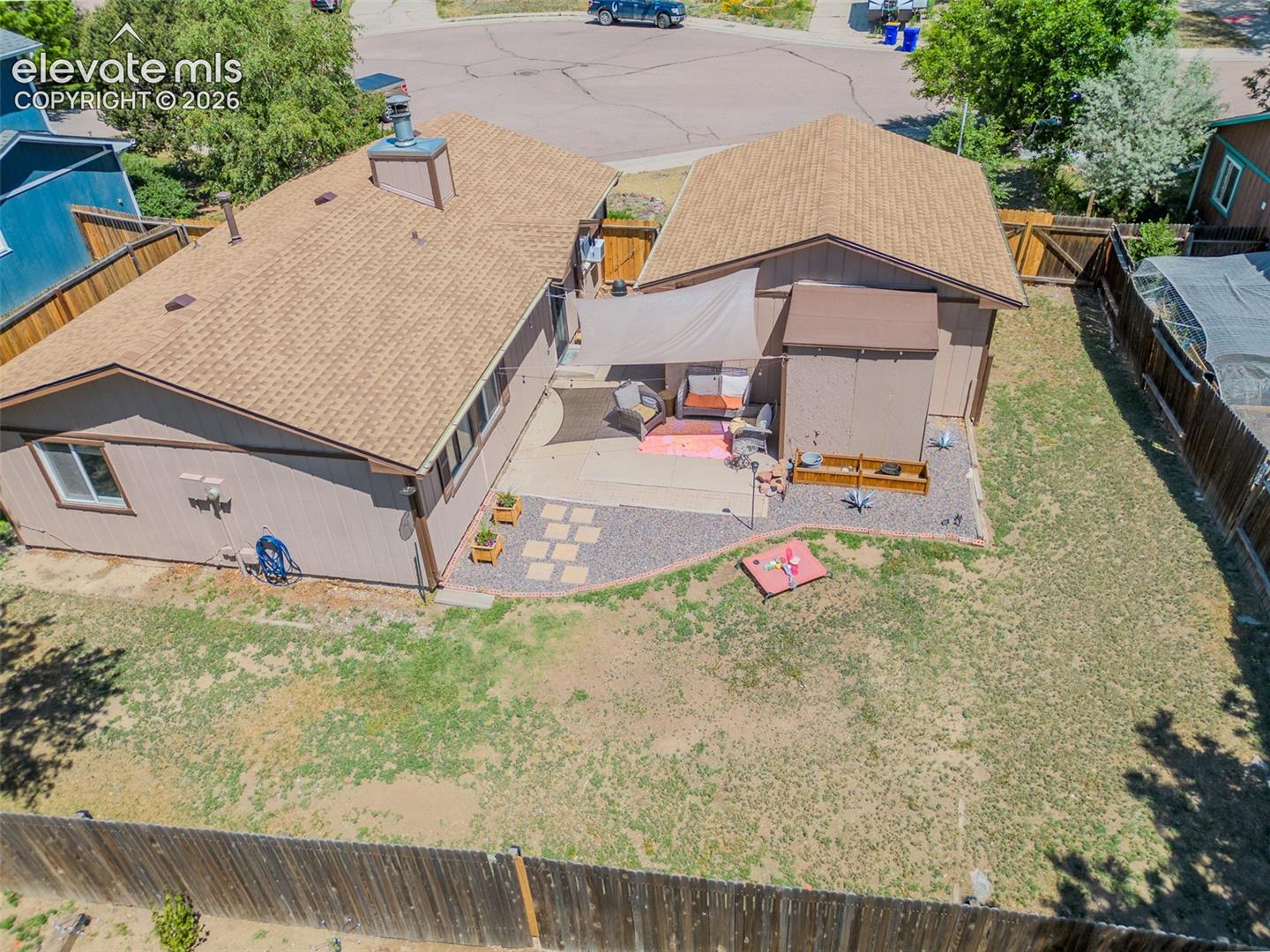 Expansive backyard featuring a large patio, gravel landscaping, and a privacy fence