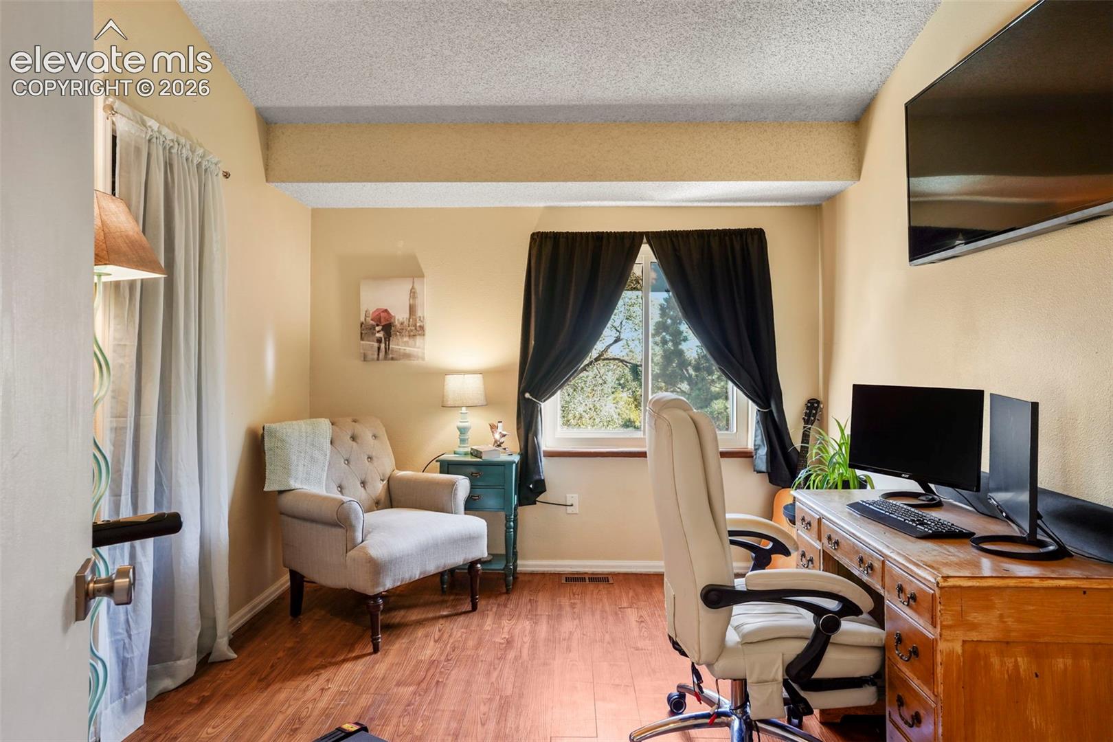 Room featuring wood-finish flooring, textured ceiling, and a window with natural light