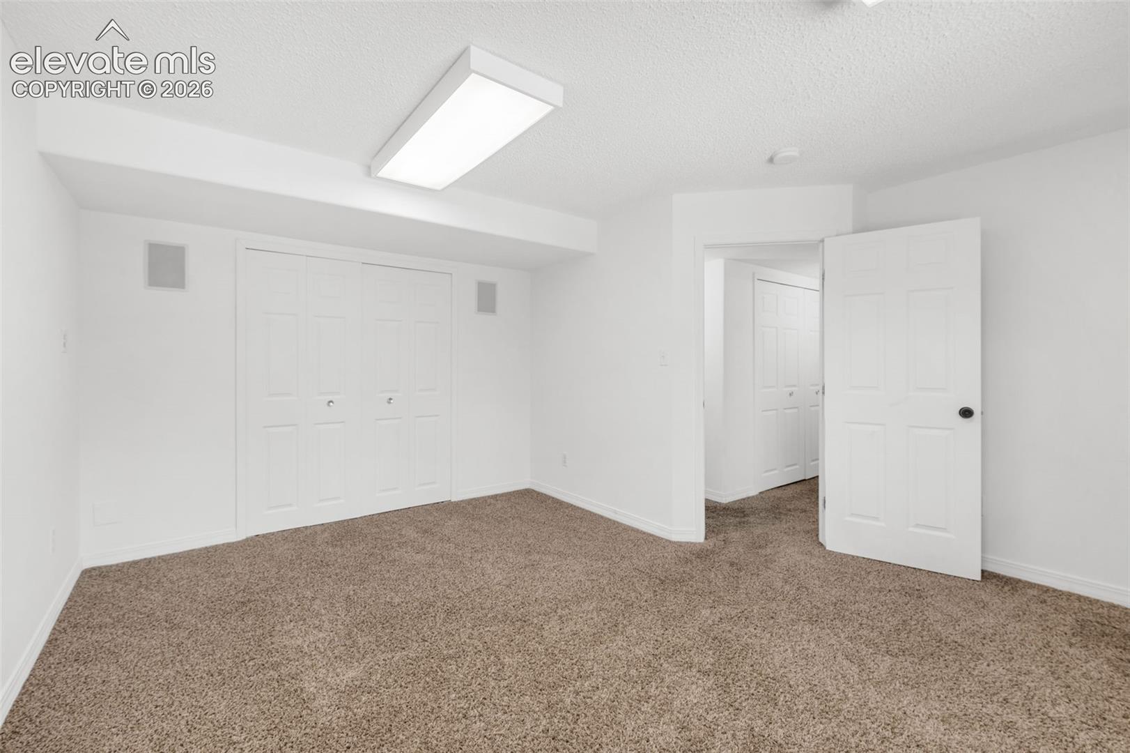Recessed ceiling speakers, bi-fold closet doors, wall-to-wall carpeting, and overhead fluorescent lighting