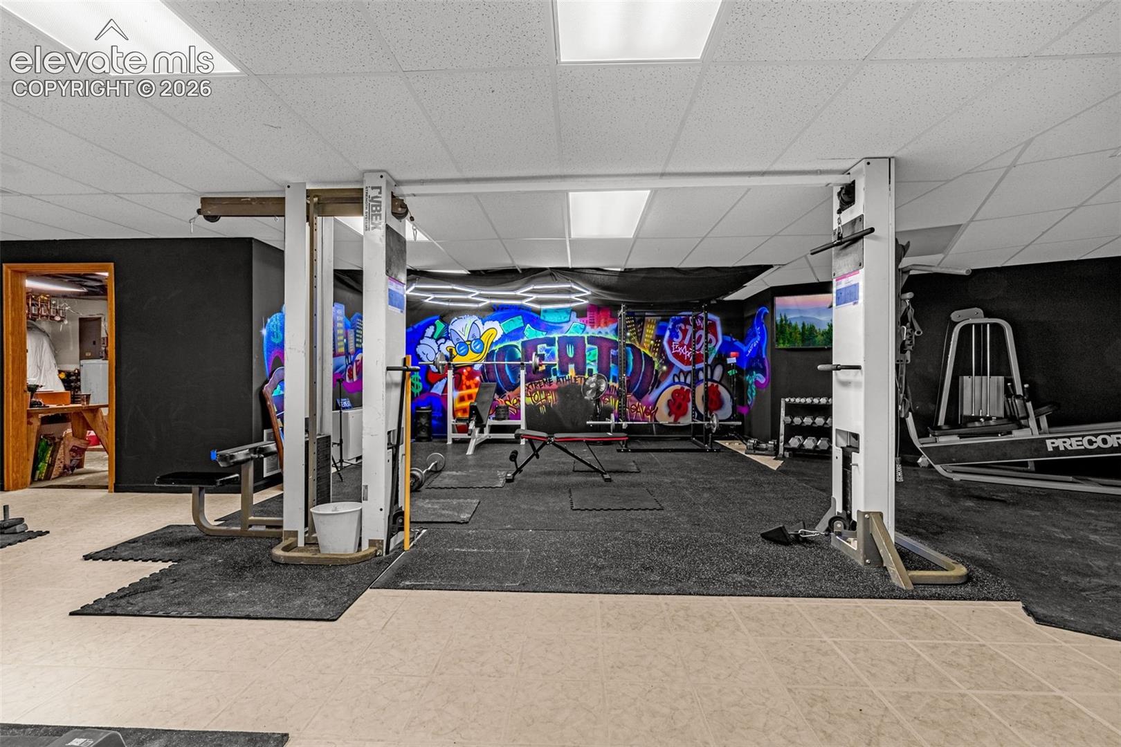 Recreational space with mixed flooring, featuring a unique wall mural and recessed lighting