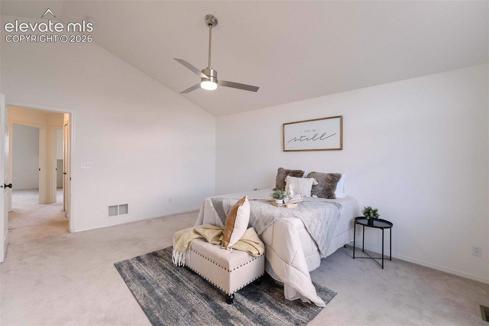 Vaulted ceiling with contemporary ceiling fan, light-colored carpeting, and neutral wall tones