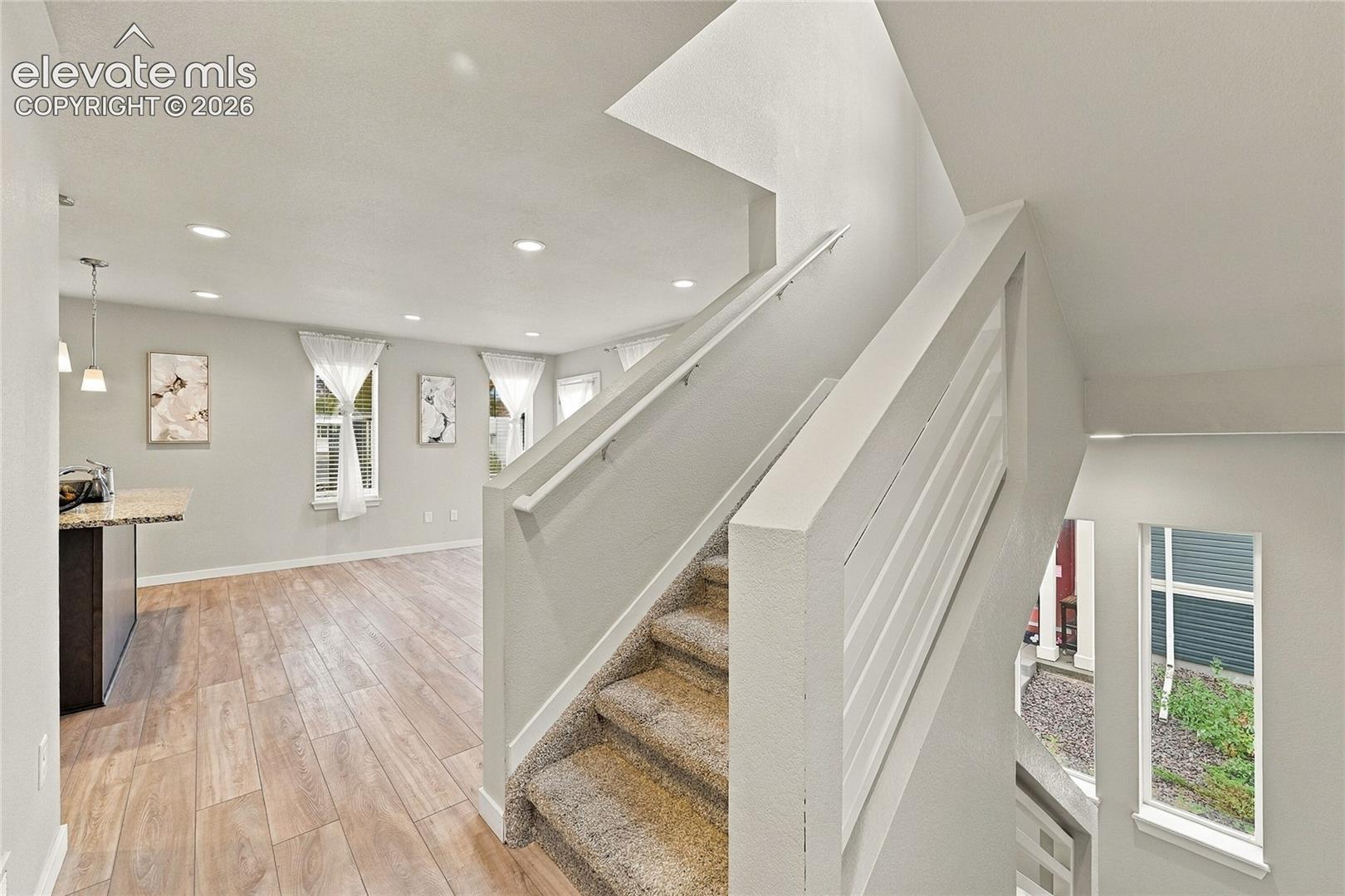 Wood-finish flooring, recessed lighting, and a modern horizontal baluster staircase
