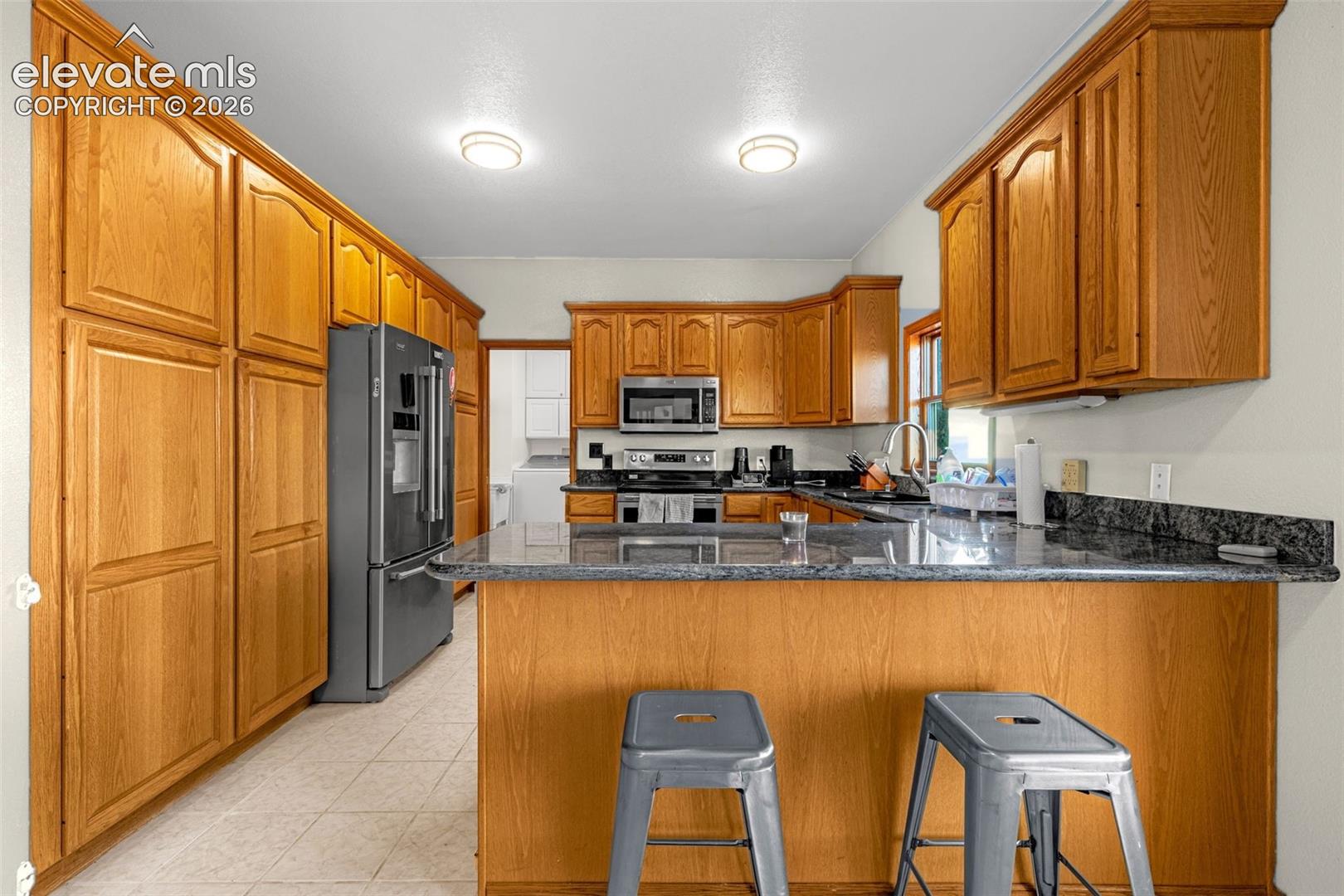 Kitchen featuring extensive wood cabinetry, dark-toned countertops, and a built-in stainless steel microwave