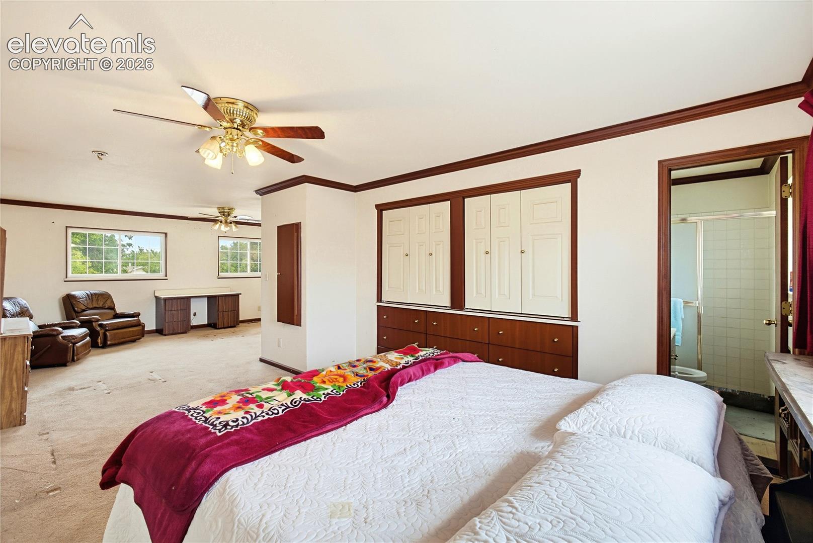 Expansive room with multiple windows, two ceiling fans, and built-in cabinetry with paneled doors and drawers
