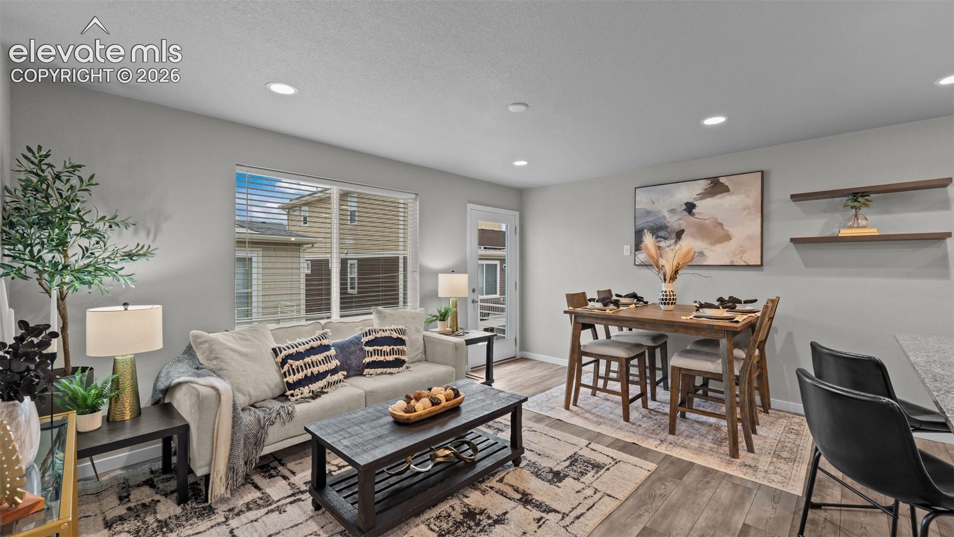 Open-concept living space featuring wood-finish flooring, recessed lighting, and wall-mounted floating shelves