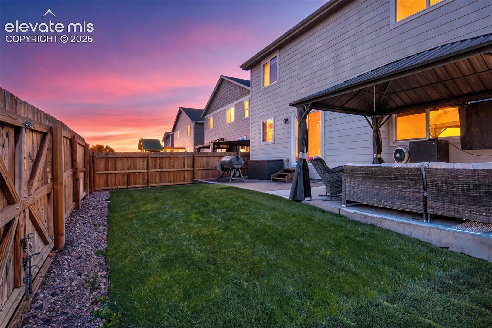 Backyard featuring a concrete patio, a metal-framed gazebo, horizontal lap siding, and a wood privacy fence
