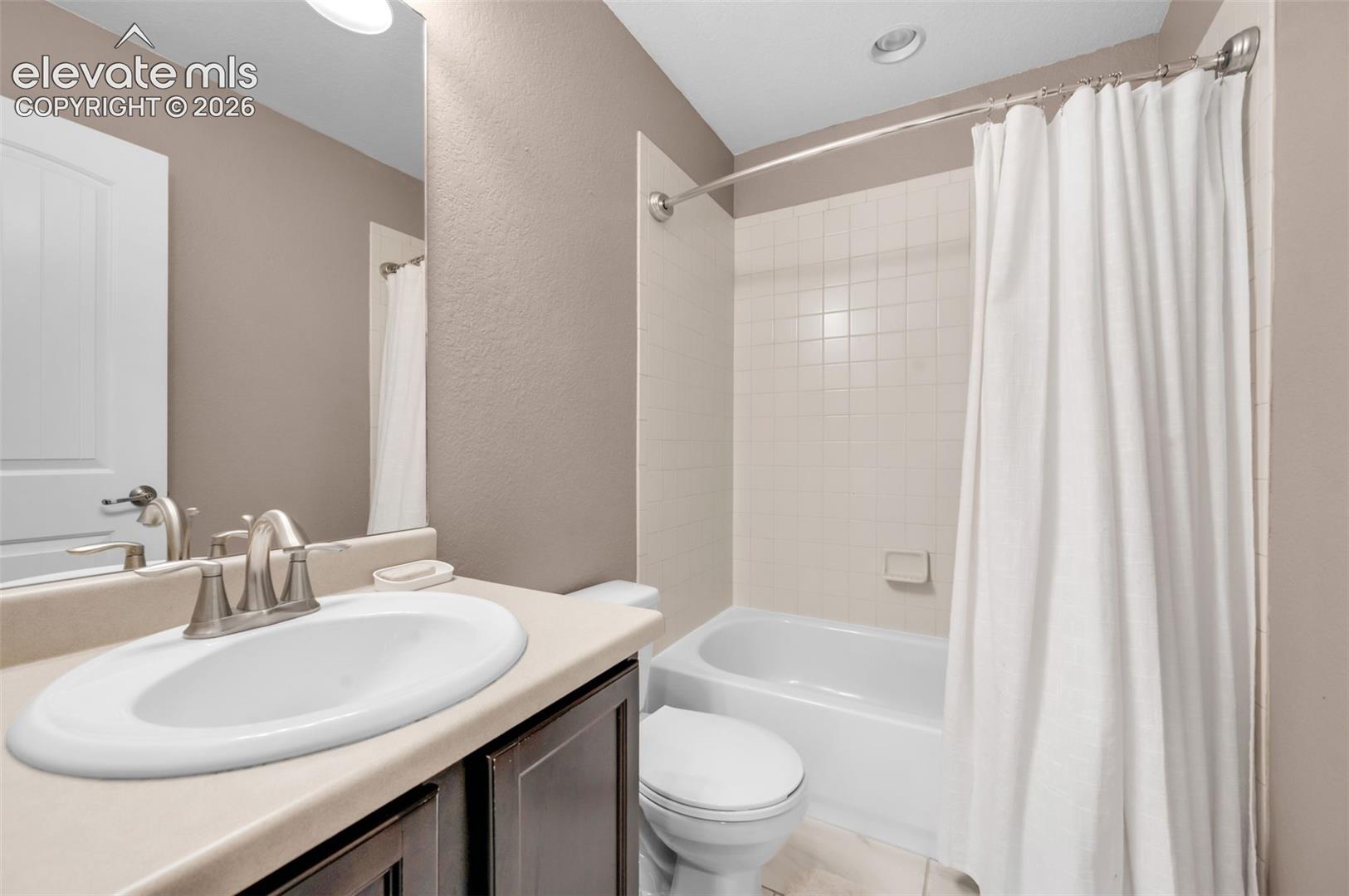 Upstairs hall bathroom featuring a vanity with a drop-in sink, brushed nickel faucet, and dark wood cabinetry