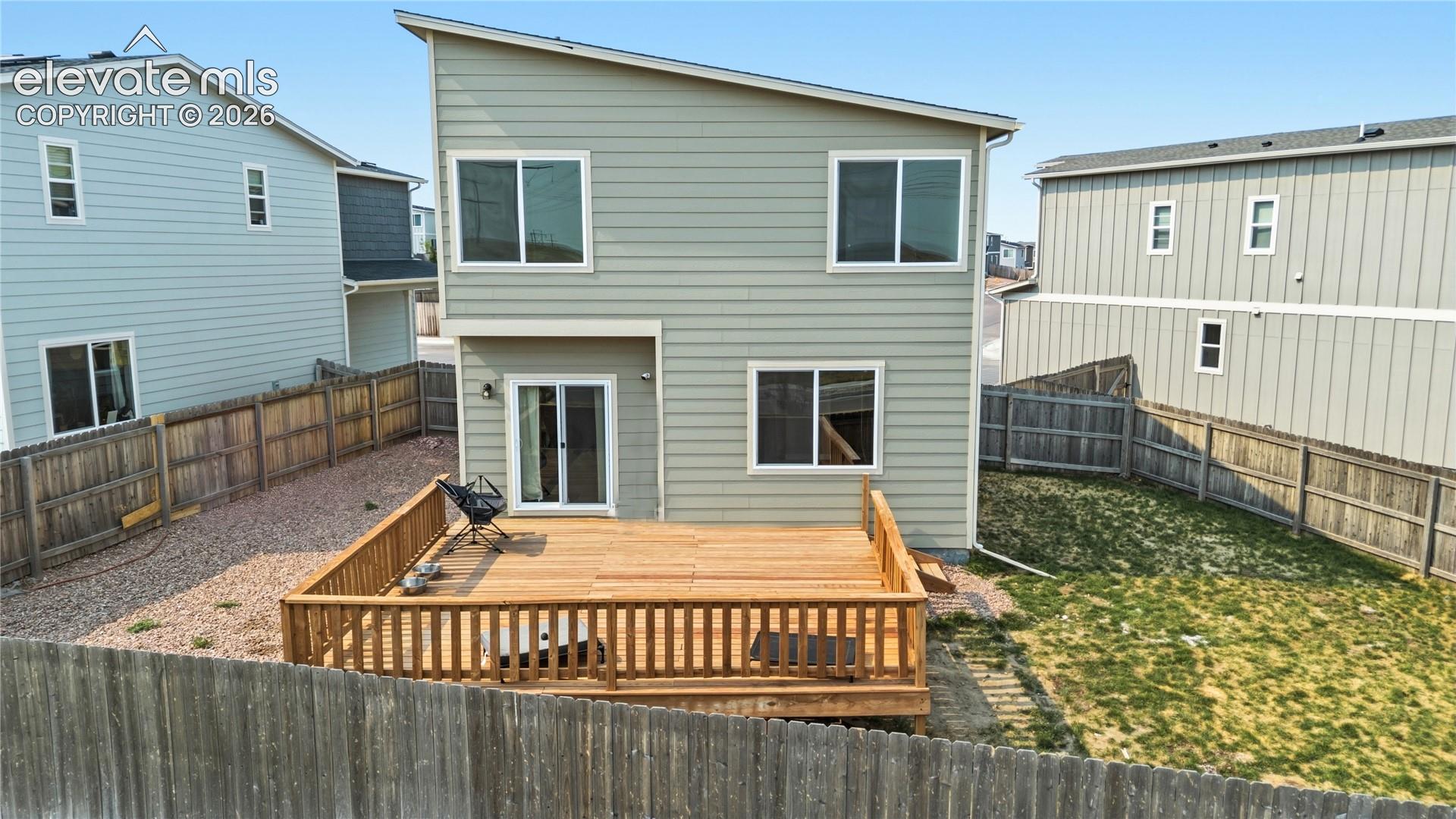Rear view of home and fenced backyard.