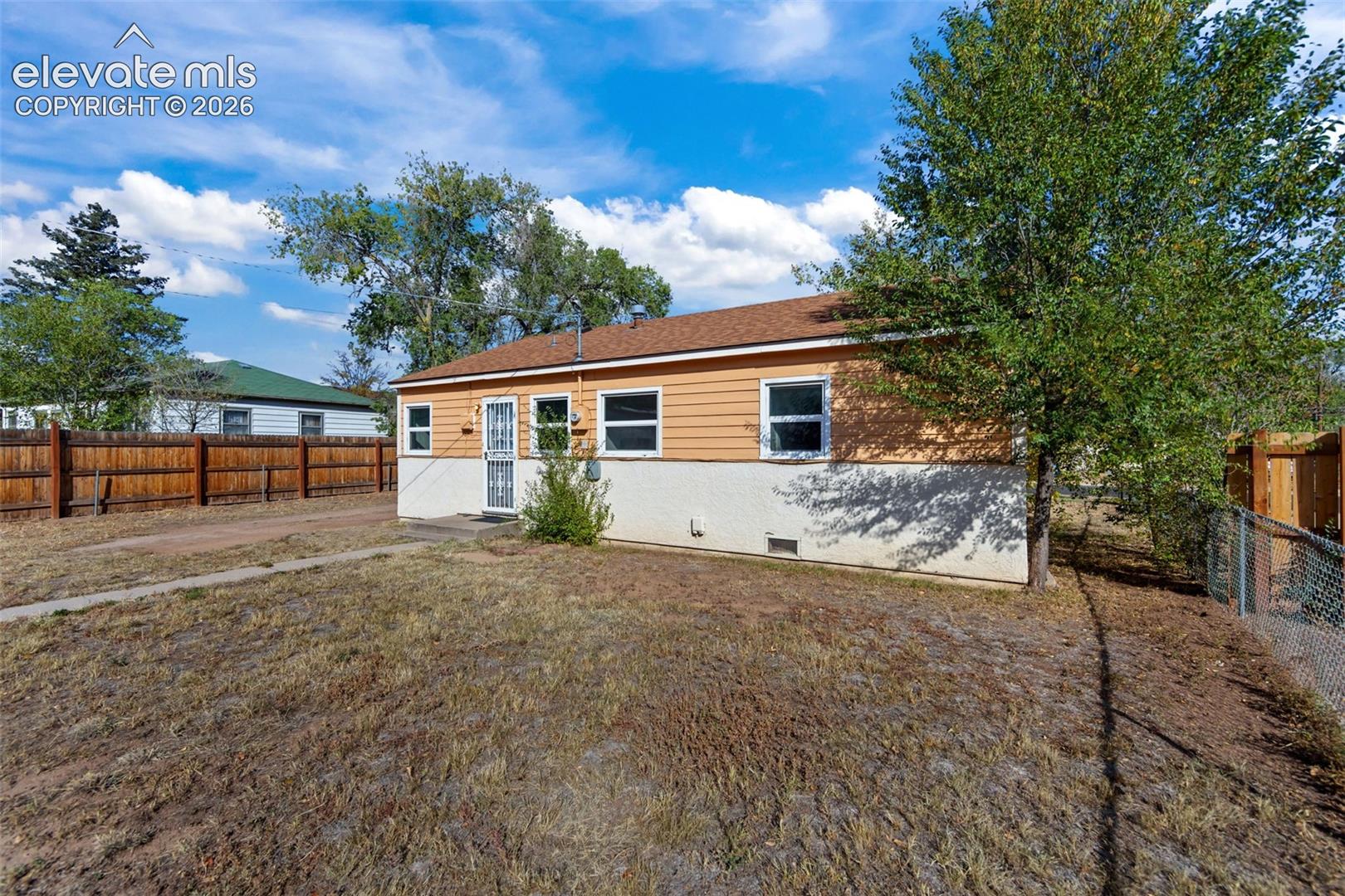 Exterior featuring two-tone siding, asphalt shingle roof, multiple white-framed windows, and a fenced-in perimeter