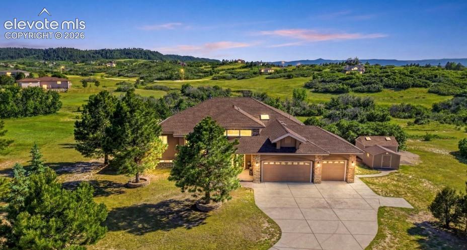 Two-car garage with overhead doors, an extended concrete driveway, and a detached storage shed