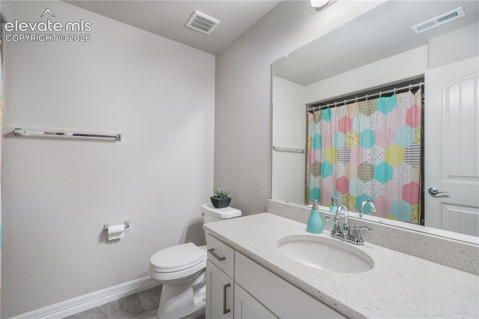 White vanity with brushed nickel hardware, integrated sink, and a speckled countertop