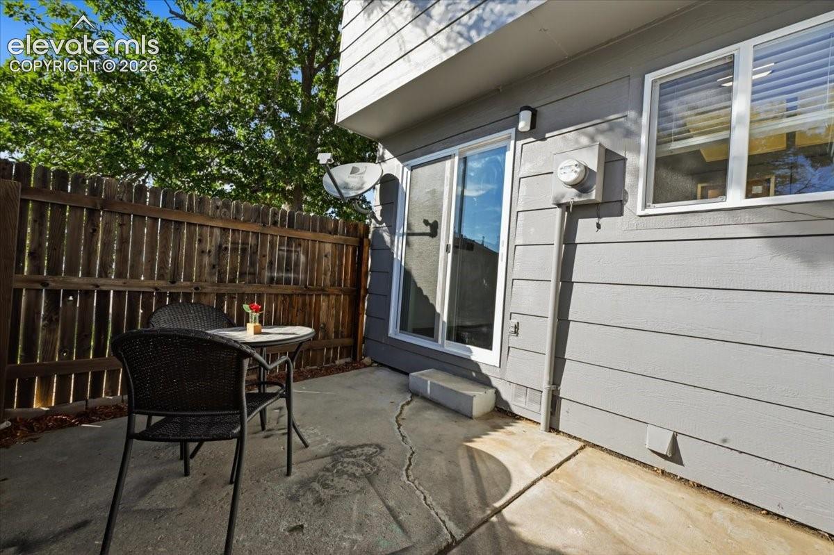 Private concrete patio with a wood privacy fence and a sliding glass door