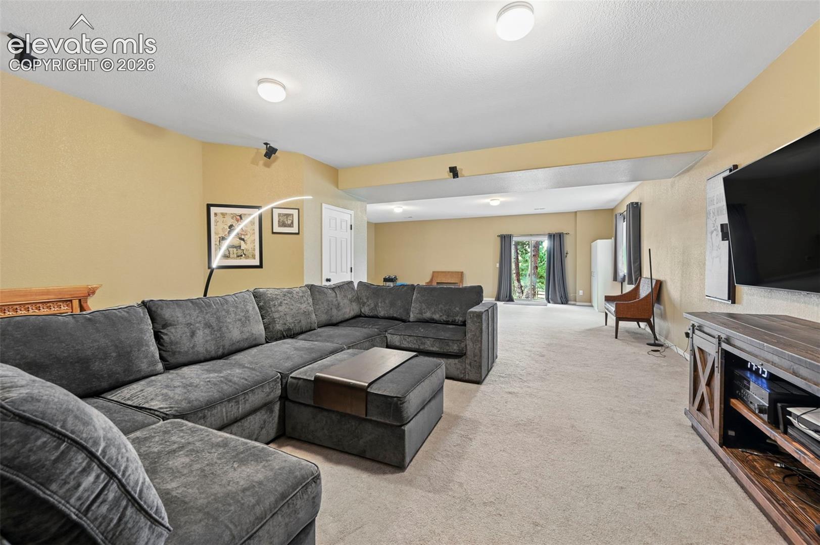 Spacious living area featuring neutral carpeting and recessed lighting