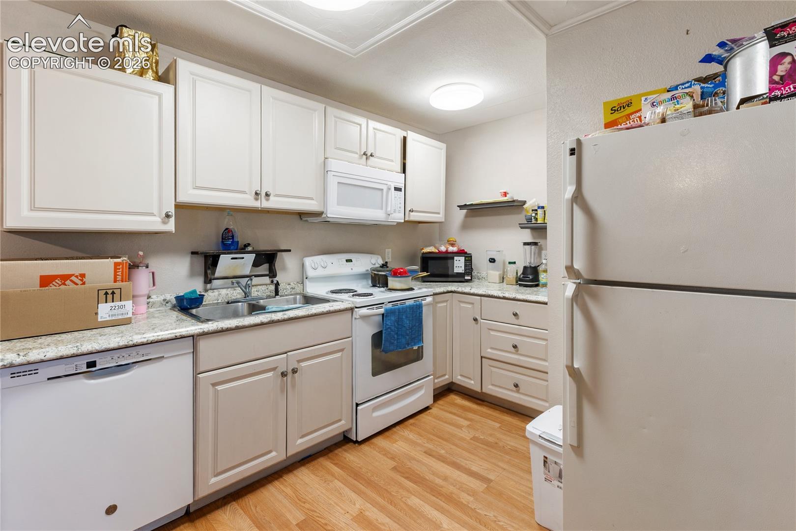 Kitchen featuring shaker-style cabinetry, light-toned stone-finish countertops, stainless steel sink with pull-down faucet, and wood-finish flooring
