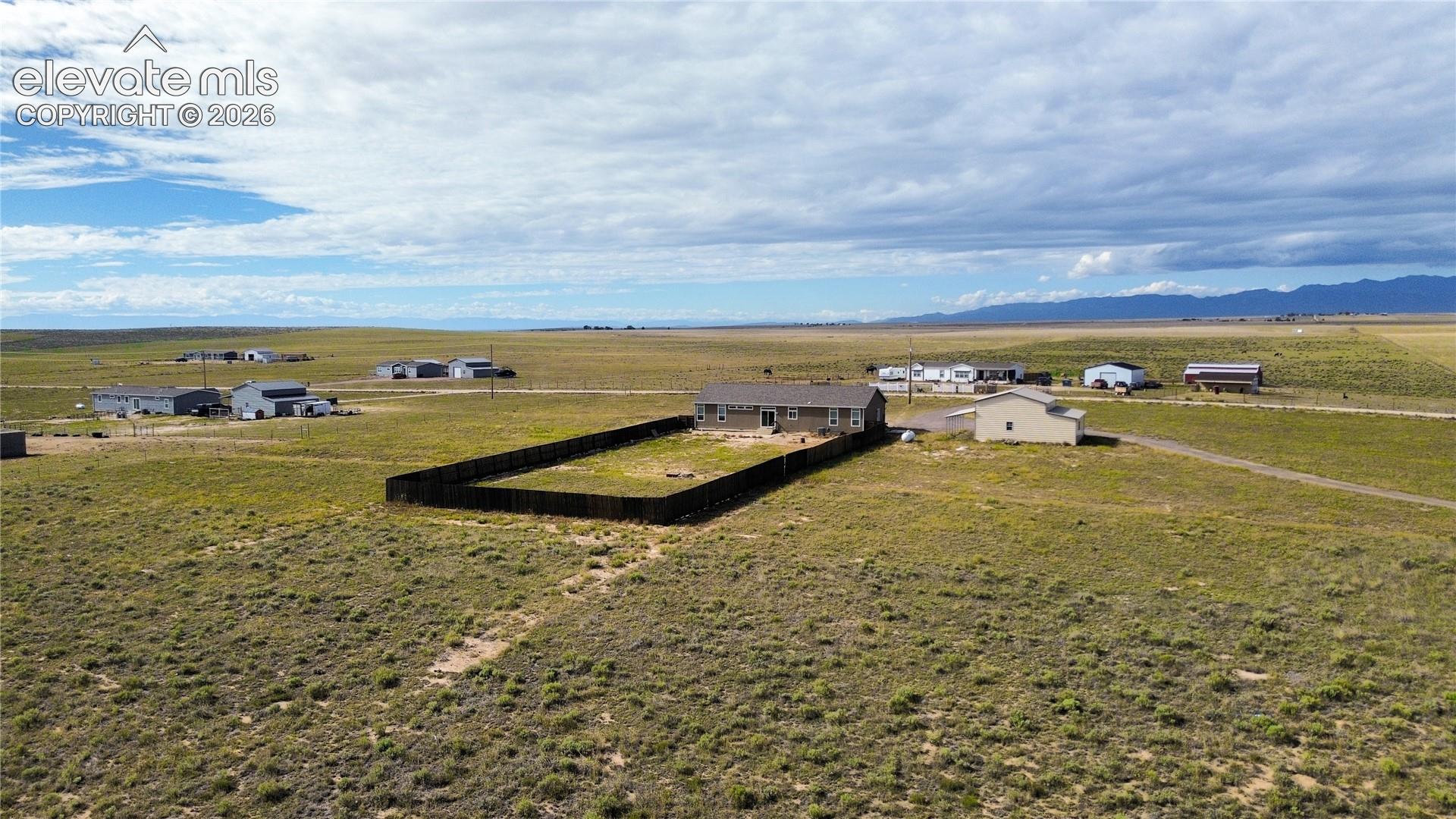 Single-story residence featuring a fenced backyard, an external structure, and expansive acreage set against a mountain backdrop