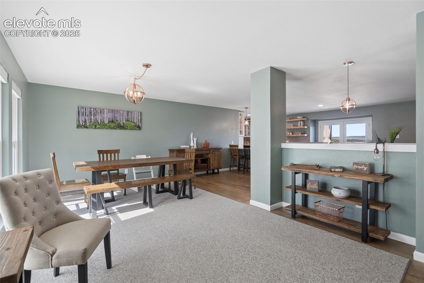 Open-concept interior featuring wood-finish flooring, two spherical pendant light fixtures, and a neutral color palette