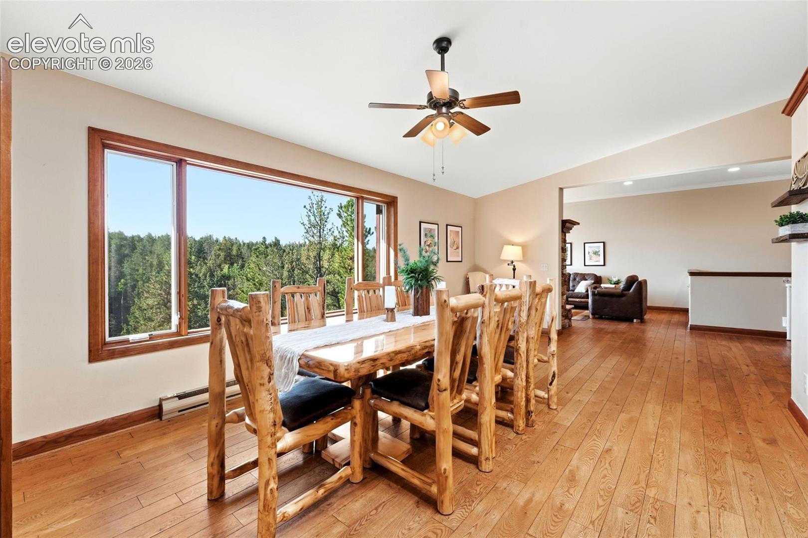 Expansive window with natural wood trim, wood-finish flooring, recessed lighting, and a ceiling fan with integrated lighting