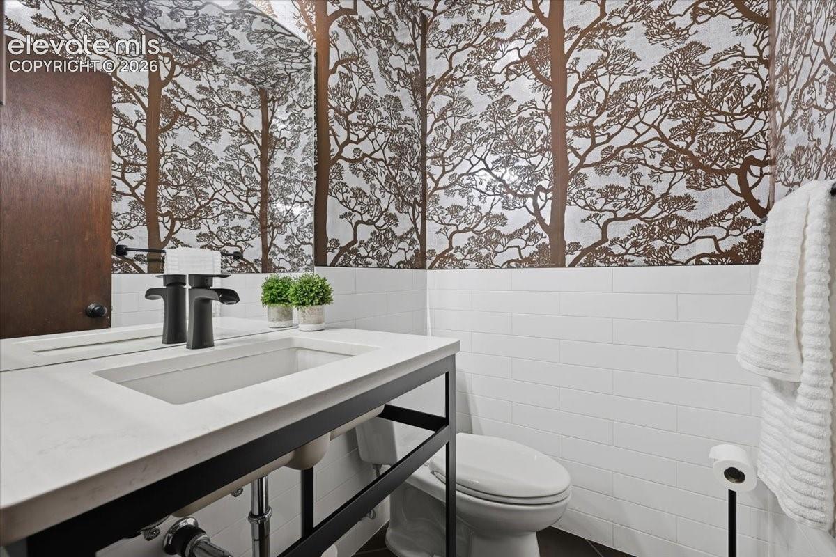 Main Level Powder room with original decorative wallpaper with white subway tile 