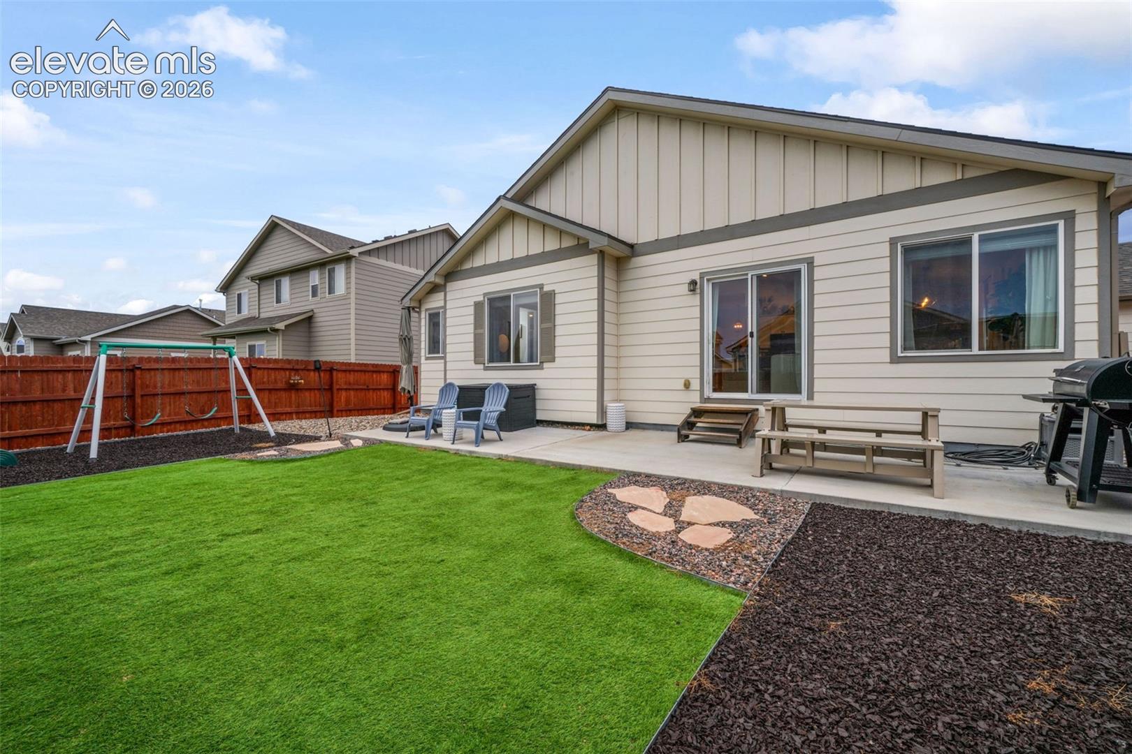 Expansive artificial turf lawn with a stepping stone pathway and mulched landscaping