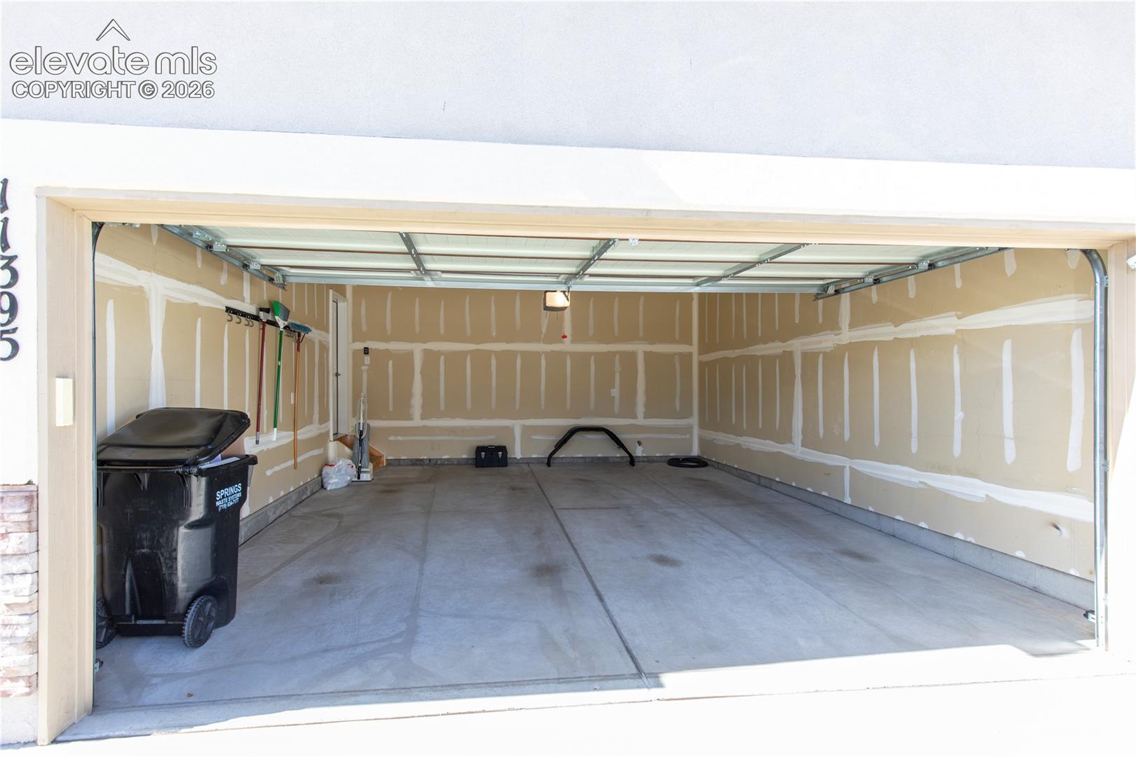 Two-car garage featuring a concrete floor, finished drywall, overhead lighting, and wall-mounted storage hooks