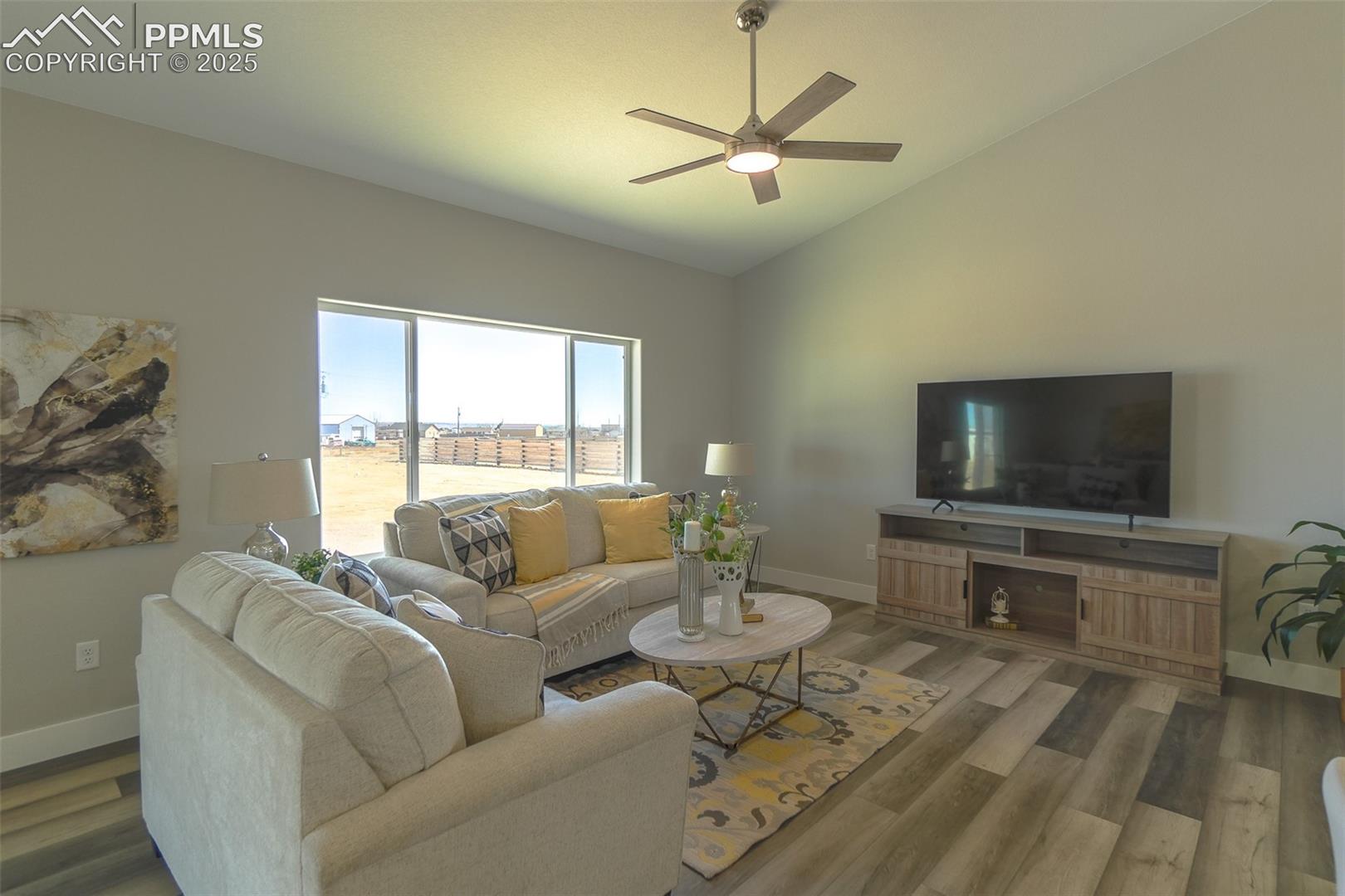 Living room with lofted ceiling, ceiling fan, LTV wood-type flooring