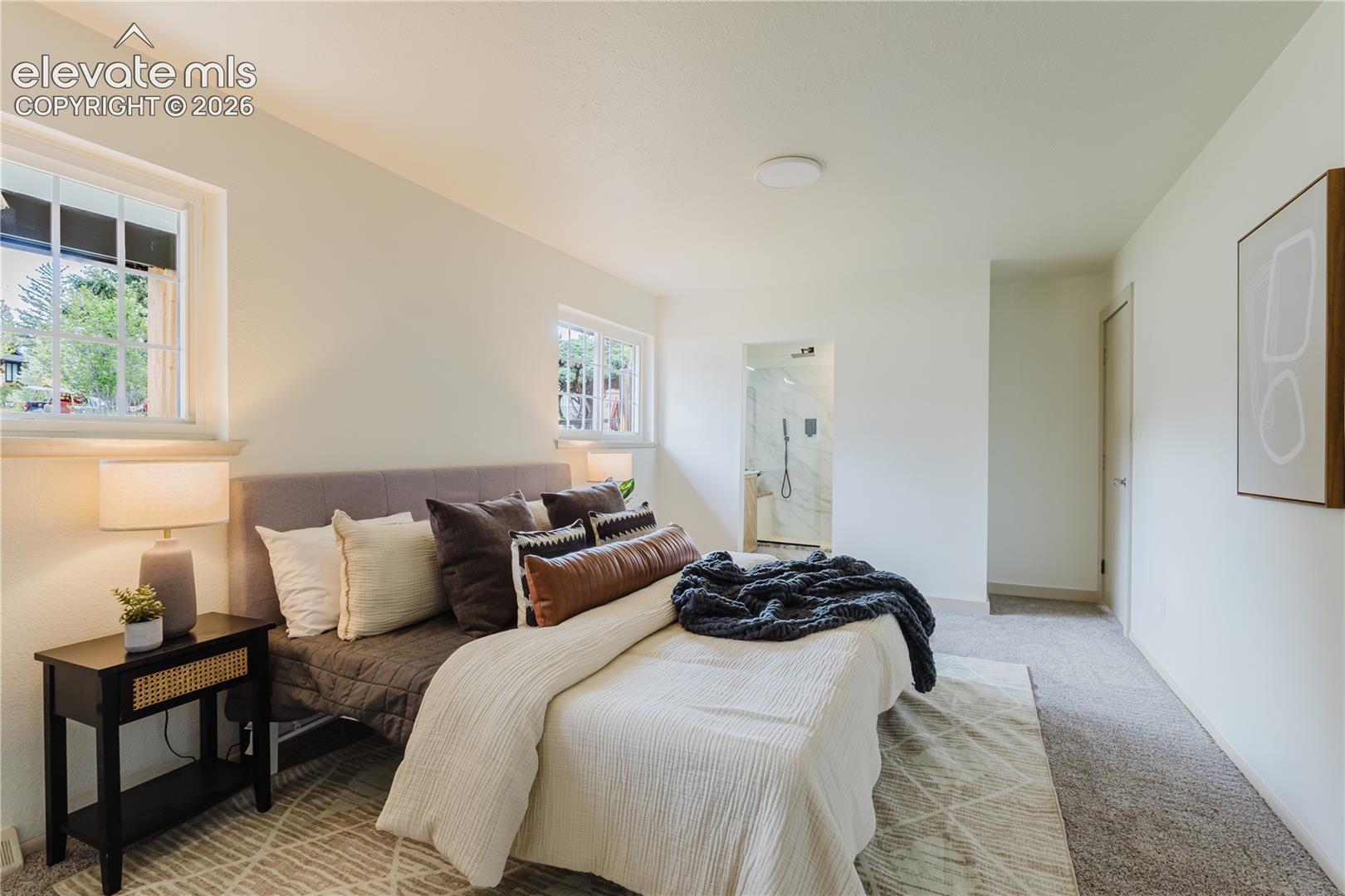 Bedroom featuring light-colored walls and two windows with white trim