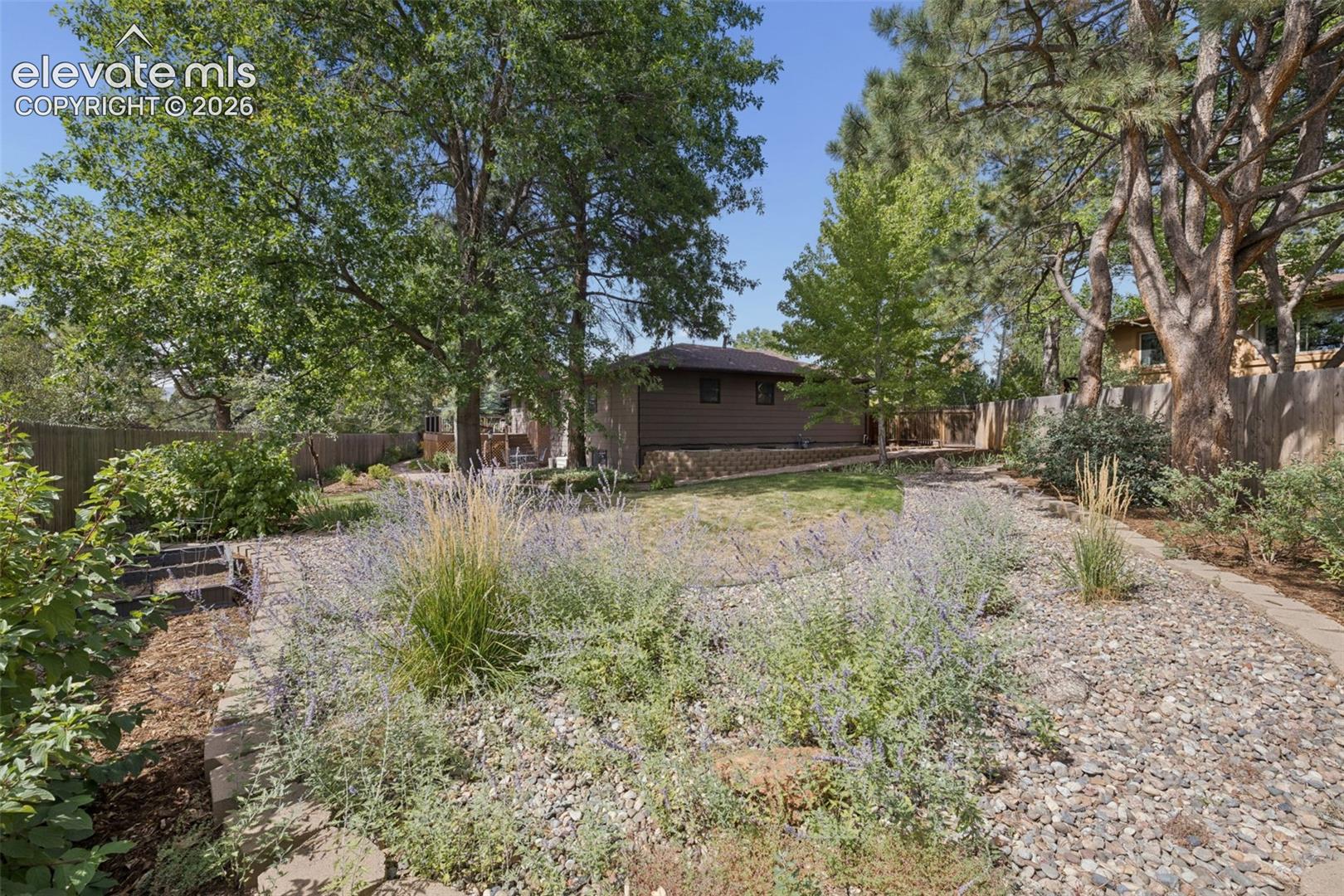 Park-like backyard has room to garden and fencing for privacy amidst mature trees.