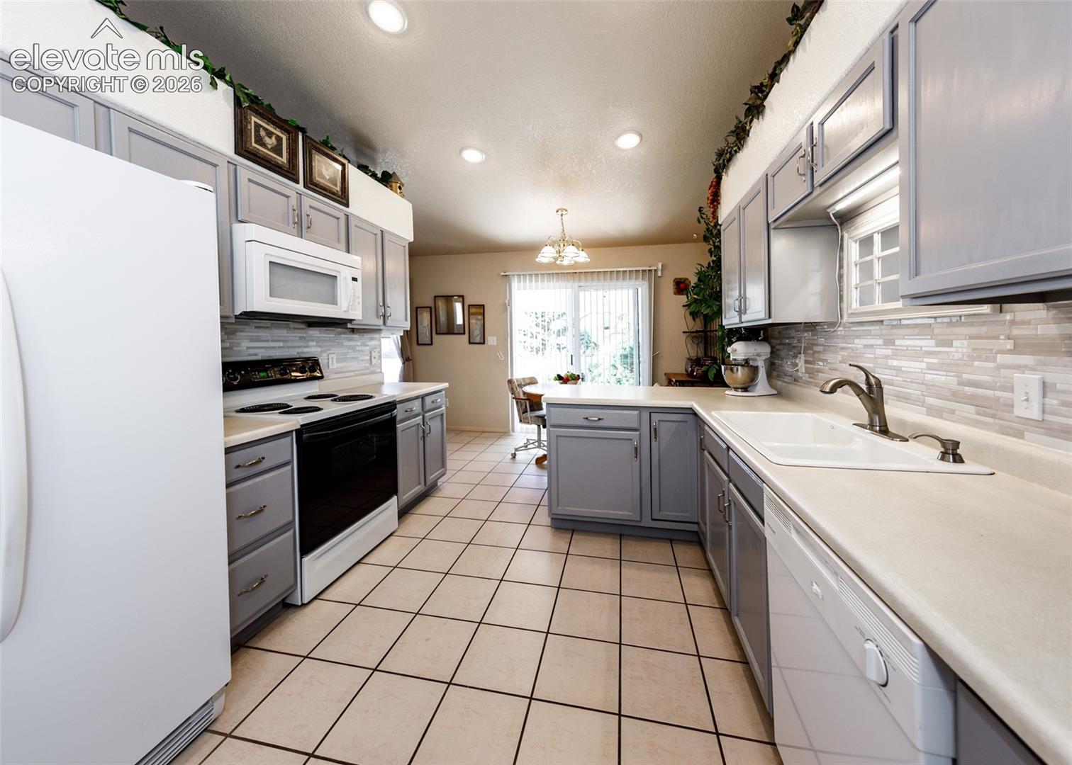 Kitchen featuring shaker-style cabinetry, tiled backsplash, recessed lighting, double-basin sink, and ceramic tile flooring