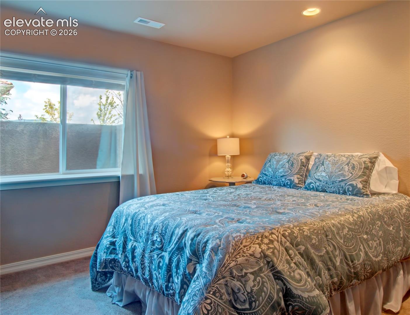 Fourth lower bedroom with Recessed ceiling lighting illuminates a room featuring a window with white sheers, textured walls, and carpet flooring. In closet storage nook or kids play fort.